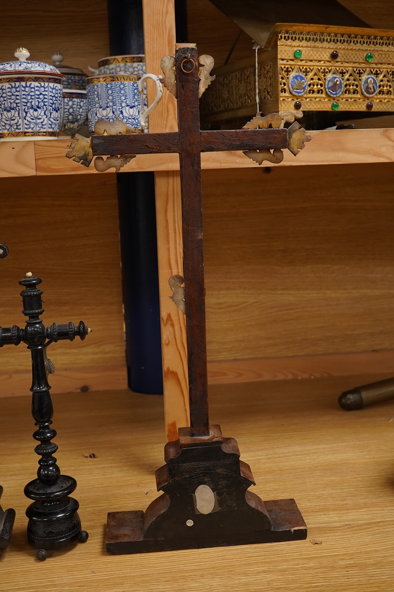 Two 19th century walnut and mother-of-pearl inlaid crucifixes and a German ebonised and white and metal mounted crucifix and a pair of Dutch or German brass tripod base cricket candlesticks, largest 56cm high (5)